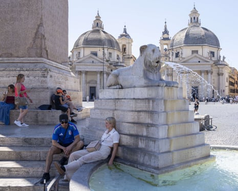 People find shade to cool off next to a fountain in Piazza del Popolo in Rome, Italy.