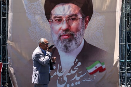 An Iranian man walks past a banner depicting Mojtaba Khamenei in Tehran.