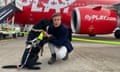 The guide dog Max and Mar Gunnarsson crouch in front of a plane