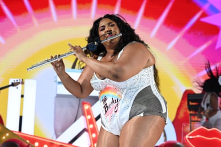 Lizzo performs onstage playing a flute.