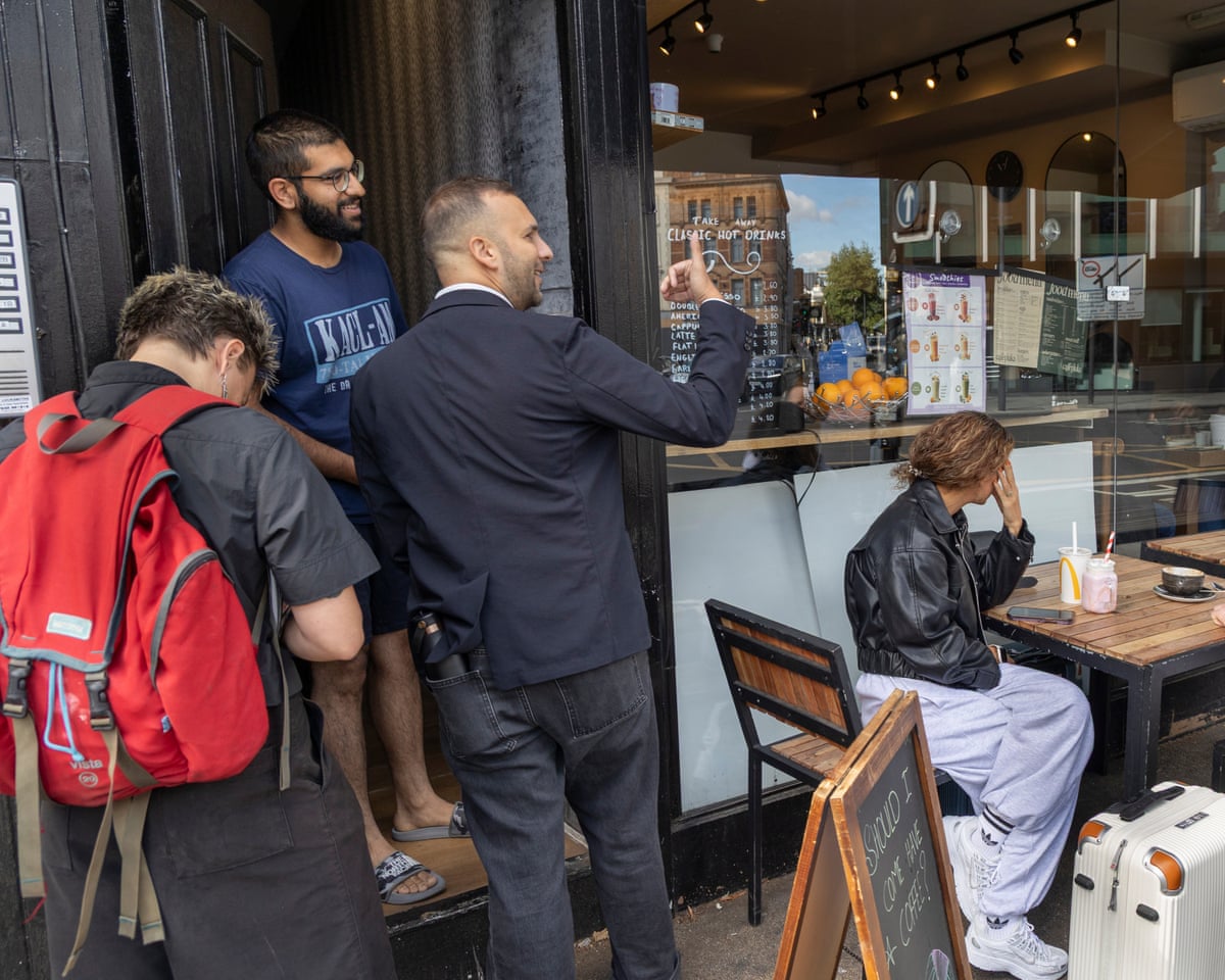 Zack Polanski talks to a man standing in his doorway next to a cafe