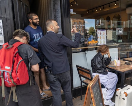 Zack Polanski talks to a man standing in his doorway next to a cafe