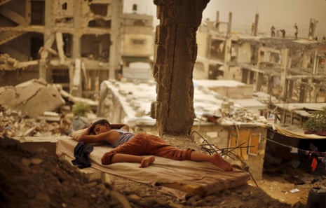 A Palestinian boy sleeps on a mattress inside the remains of his family’s house, that witnesses said was destroyed by Israeli shelling during a 50-day war in 2014 summer, during a sandstorm in Gaza September 8, 2015.