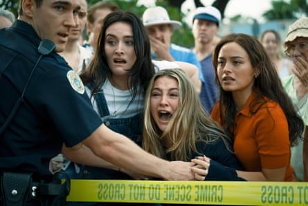 Three women are held back behind police tape by a police officer