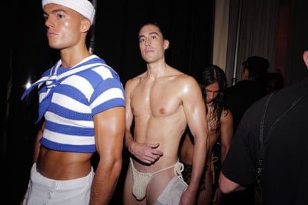 Models dressed in knitwear wait backstage at a fashion show