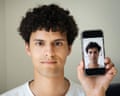 Isaaq Tomkins holding up a mobile phone showing a radically altered image of his face