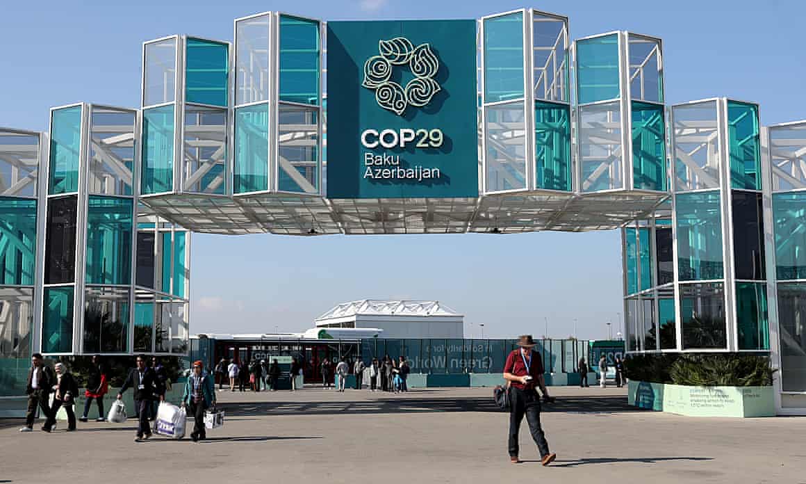 People beneath the entrance to the Cop29 venue