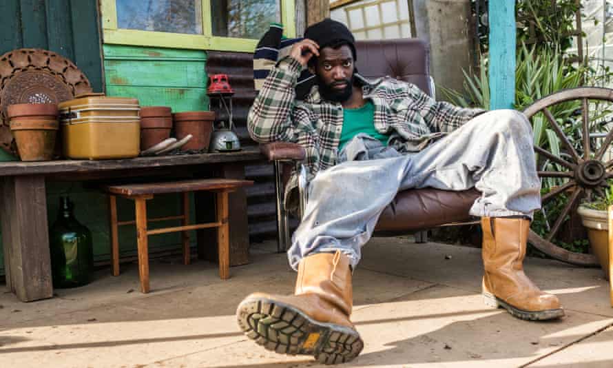 Malachi Kirby as Tufty sprawls in a low chair, looking cross, on the allotment.