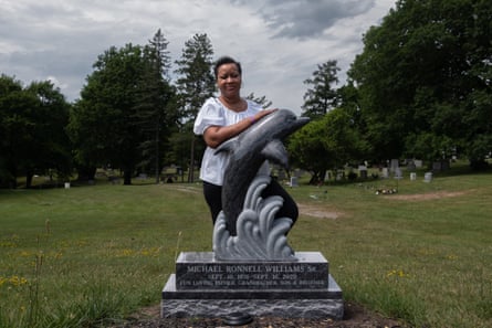Michael Williams’s aunt, Paula Tyrell, stands by his headstone at Oakwood Cemetery in Syracuse, New York.