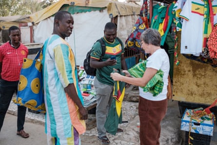 Жена купува футболна фланелка на Сенегал от Усейну Тиун (в средата вляво).