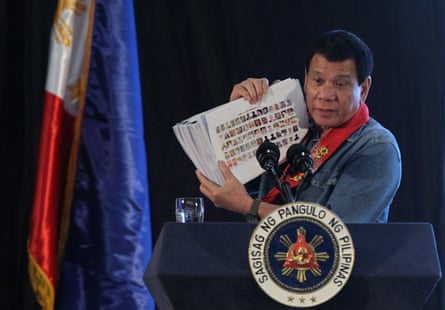 Then-president Rodrigo Duterte holds a compilation of pictures of people allegedly involved in drugs as he speaks at a meeting in Davao city, southern Philippines, in February 2017
