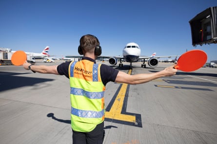 Jack Quantick-Thorne stands with his back to the camera directing planes with his paddles.
