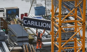 A worker guides down a sign showing the name of Carillion.
