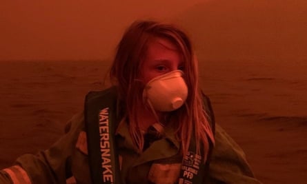 A child sits in a boat offshore from Mallacoota in coastal Victoria as a bushfire raged onshore on New Year’s Eve 2019.