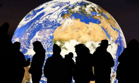Silhouettes of people in front of a globe model of Earth – artist Luke Jerram's Floating Earth.