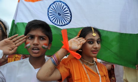 Students salute next to a flag as they sing the national anthem in Hyderabad