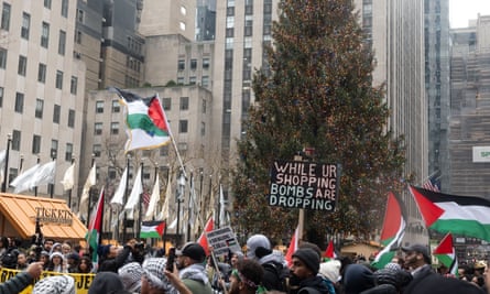 Filistin yanlısı protestocular Noel Günü'nde New York City'deki Rockefeller Plaza'da.  Bir tabelada şunlar yazıyor: 