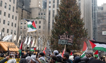 Pro-Palestine protesters at Rockefeller Plaza in New York City on Christmas Day. One sign reads: 'While UR shopping, bombs are dropping.'