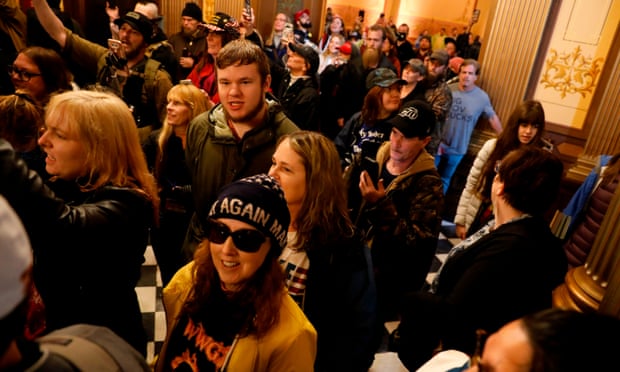 Protesters carrying mobile phones try to enter the Michigan house of representatives chamber during an anti-lockdown protest in Lansing on 30 April.