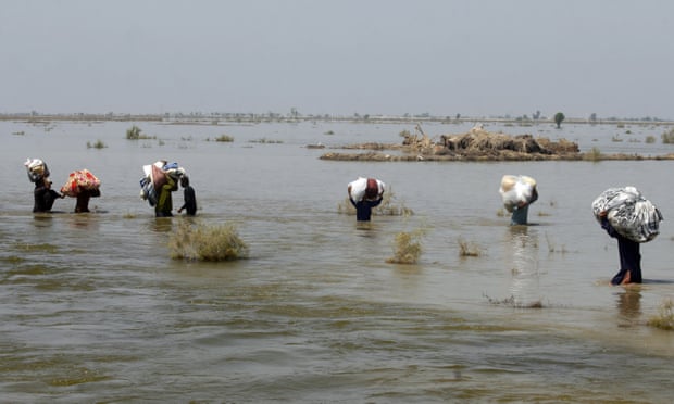 Las víctimas de las fuertes inundaciones causadas por las lluvias monzónicas transportan ayuda a través del agua de la inundación en el distrito Qambar Shahdadkot de la provincia de Sindh.
