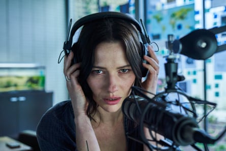 A woman with headphones on sitting in front of a mic