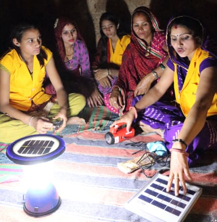 Hansa Chaudhary sitting with a group of women around a solar lamp