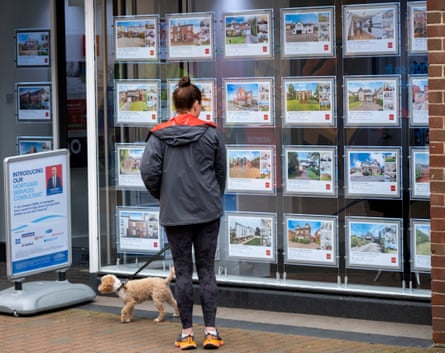 Woman looking in the window at properties advertised in an estate agent