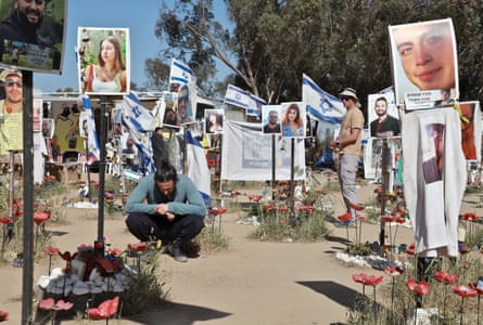 Israelis and foreigners at the site of the Nova festival surrounded by pictures of the dead.