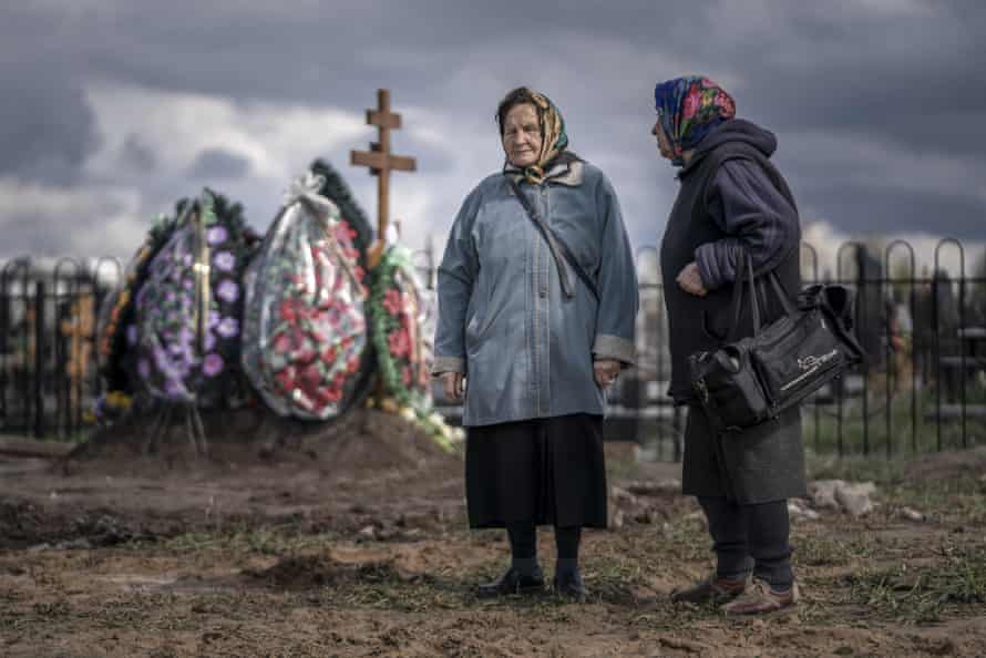 Two women sing traditional songs during a burial at a cemetery in Borodyanka, Ukraine.