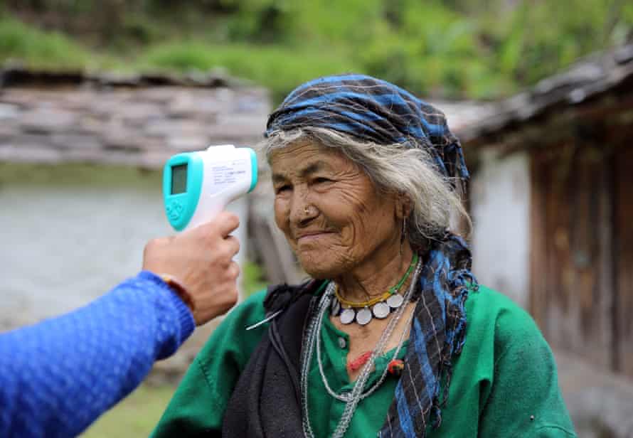 Baisakhi Devi, 90, has her temperature checked by a community health worker in Durmi.