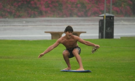 Surfer Adrian Zimmerman is pulled with rope attached to an electric bike as he skims with a board on a fully soaked lawn under heavy rain at Cannon Park in Carlsbad, California.