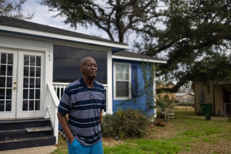 An older man in front of his house.