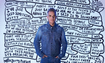 Robbie Williams standing in front of one of his artworks, a large canvas with anxious thoughts such as 'I'm getting on so well with this person it's draining me' and 'I like this one but we have nothing in common' written in many bubbles