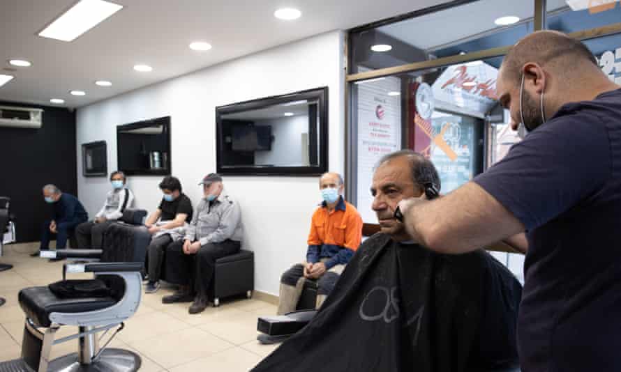 Barber Moustafa Elrifai cuts a customer’s hair at his salon in Lakemba on Monday morning as greater Sydney reopened to those who have been fully vaccinated.