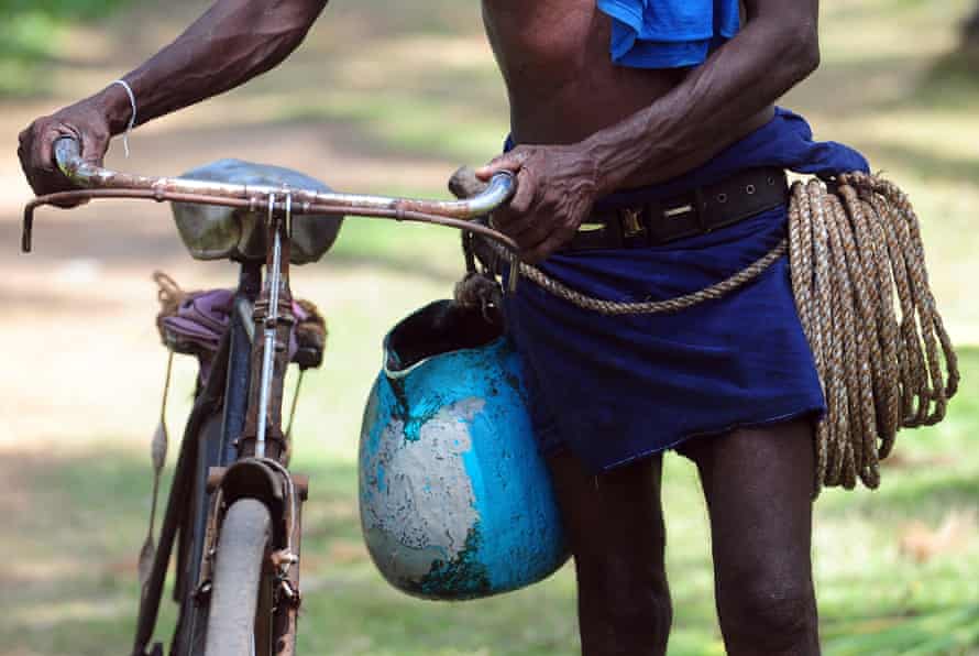 A Sri Lankan toddy tapper with his rope to climb the tall palms and clay pot to collect sap.