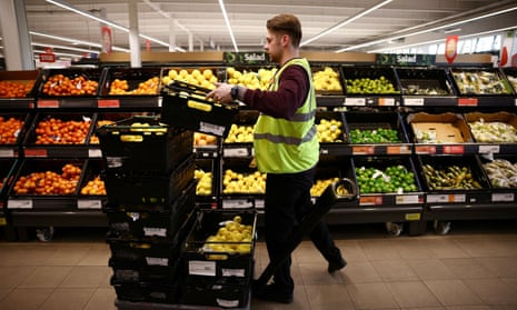 A Sainsbury’s employee arranges produce inside a  supermarket in Richmond, west London.