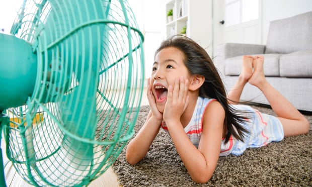 Girl lying down on floor at home in front of an electric fan