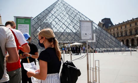 People with health passes wait to enter the Louvre museum in front of the Louvre Pyramid in Paris. 