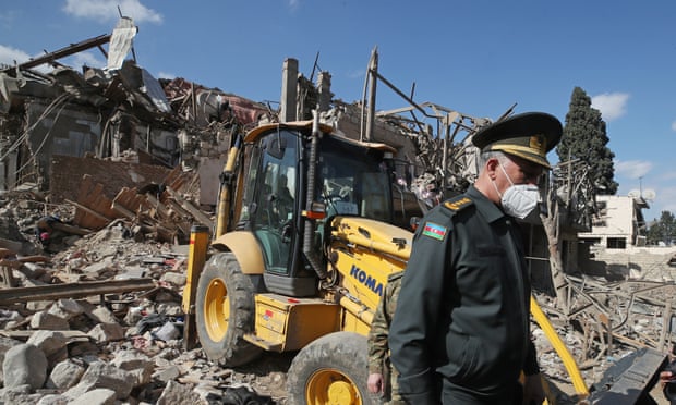 An Azerbaijani officer stands amid the rubble of a residential building destroyed in the fighting in Ganja