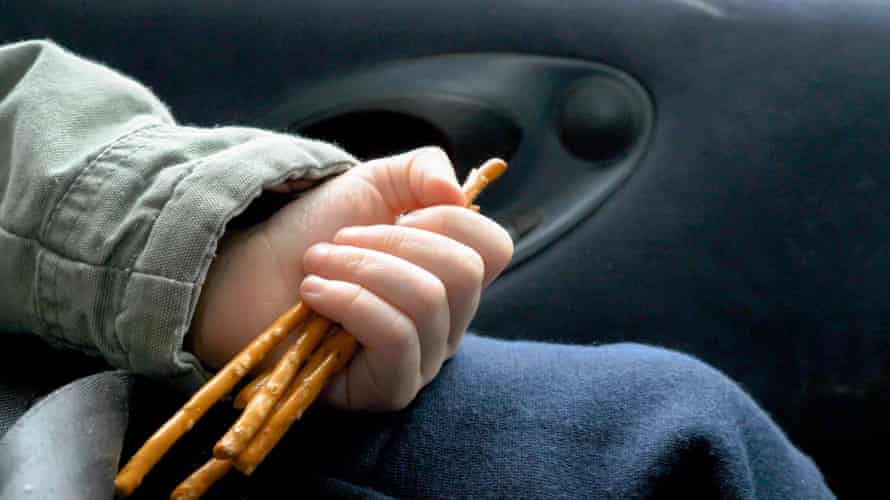 Close up view of child's hand holding and eating cookies while traveling by car.
