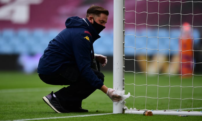 A member of ground staff disinfects the goal posts at Villa Park