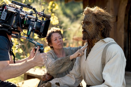 A camera being pointed at a man with a special-effects costume and a woman in a grey dress.