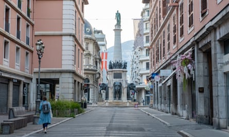 A street with pale pink classical buildings and a statue on a plinth.