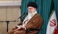 Ayatollah Ali Khamenei sitting behind a microphone, with an Iranian flag behind him