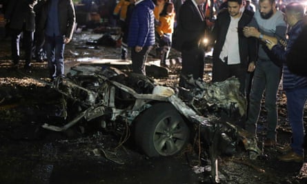 People and security forces gather around the wreckage of a car at the scene of a blast in Ankara.