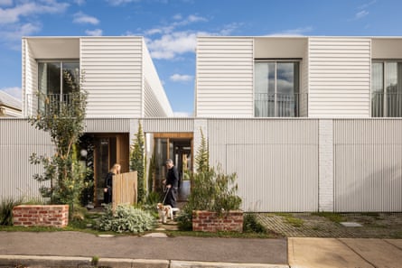 Wide view of two white townhouses with a person in each neighbouring yard