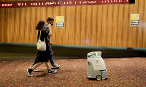 A couple walks past a cleaning robot at the lobby of a cinema in Singapore, 13 July 2020.