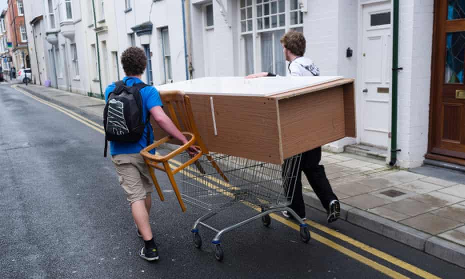 Two students people men moving furniture wheeling a wardrobe on a shopping trolley aberystwyth wales ukD5GK94 Two students people men moving furniture wheeling a wardrobe on a shopping trolley aberystwyth wales uk