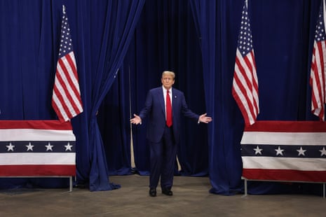 a man in a blue suit and red tie stands in front of a blue curtain