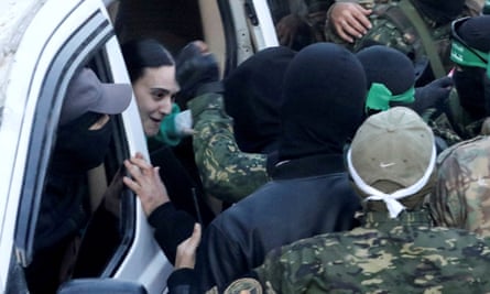 Hamas militants gather around a vehicle as they hand over Emily Damari